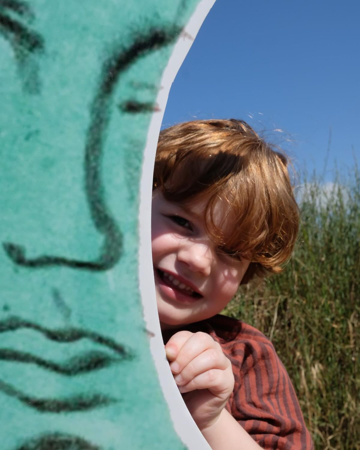 A child peeking out from behind an arch
